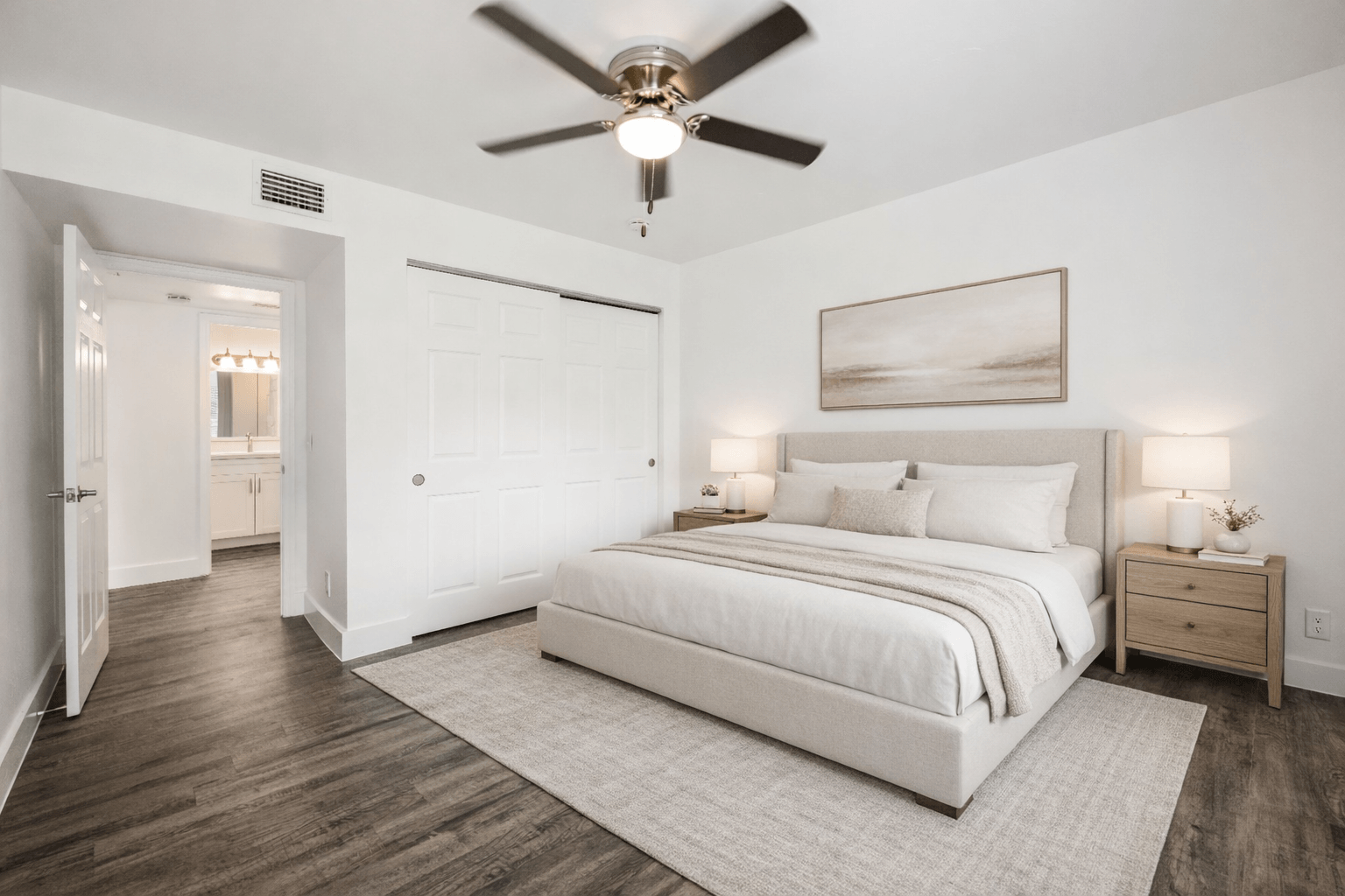 A bedroom with a large bed, a ceiling fan, and a painting on the wall.